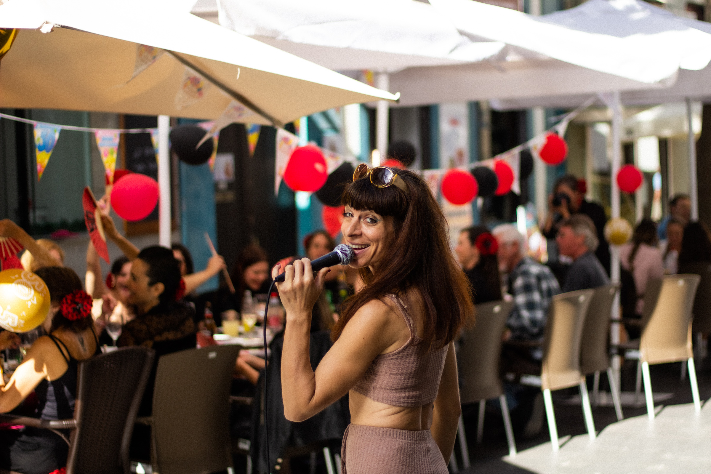  Cinzia Mare cautivando a la multitud con su actuación musical durante una comida, irradiando energía y talento en un ambiente festivo y animado.